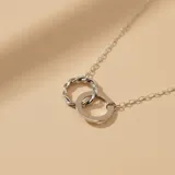 Collar de cadena fina en plata 925 con dije compuesto por dos aros entrelazados, uno de diseño liso y otro con textura trenzada.
