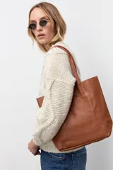 Bolso tipo tote de cuero vacuno con textura granulada, color tostado. Presenta doble asa larga para llevar al hombro y un diseño amplio y minimalista.
