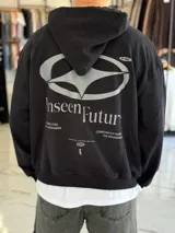 Hoodie de corte boxy fit color beige, con capucha y estampa gráfica verde en la espalda con la inscripción "Unseen Future" y detalles tipográficos.