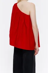Blusa roja de tafeta con un hombro descubierto, escote recto con volantes y corte holgado.