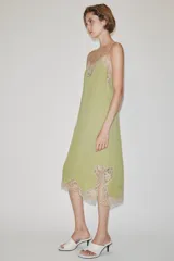 Vestido midi confeccionado en hilatura de viscosa, de color verde con detalles de encaje a contraste en el escote y el bajo. Cuenta con escote recto y tirantes finos ajustables.