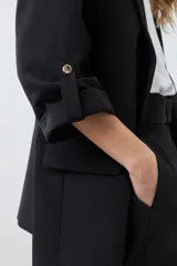 Blazer de corte recto y diseño minimalista, color blanco, con solapas clásicas, bolsillos frontales con solapa y mangas tres cuartos con detalle de botones.