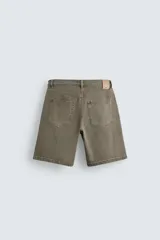 Bermuda de denim de algodón, color verde claro lavado, de corte recto y tiro medio. Presenta cinco bolsillos y cierre frontal con cremallera y botón.