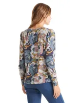 Buzo de hilado fino con cuello redondo y mangas largas. Presenta un estampado floral en tonos grises, azules y ocres, con detalle de botones decorativos en el lateral inferior.