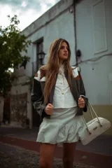Campera de cuero de silueta oversize y corte corto, con cuello camisero verde oscuro, detalles en pelo de vaca marrón y blanco, y mangas amplias.