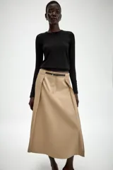 Falda midi de tiro alto en color beige, con diseño evasé y pliegues laterales. Incluye un cinturón fino a contraste en color negro con hebilla metálica y cierre frontal con cremallera y gancho.