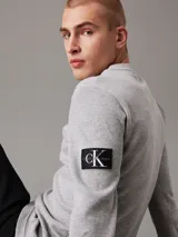 Remera gris de punto gofrado, corte slim, cuello redondo, mangas largas y puños de canalé.