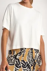 Remera de corte oversize, color blanco, confeccionada en tejido acanalado con mangas cortas y cuello redondo.