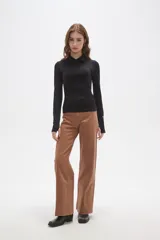 Remera de manga larga color negro, confeccionada en tejido técnico al cuerpo. Presenta cuello tipo polo con cierre frontal parcial y puños con abertura para el pulgar. Incluye un pequeño logo estampado en la manga.