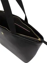 Cartera Tommy Hilfiger tipo tote color negro, confeccionada en poliuretano con acabado liso. Tiene doble asa superior, compartimento principal con cierre de cremallera y logo de metal en la parte delantera.