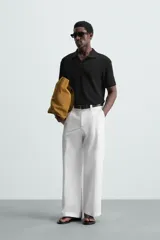 Polo negro de manga corta con cuello solapa y abertura frontal. Presenta un tejido jacquard con textura geométrica sutil.