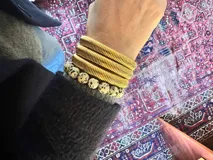 Anillo elástico de cuentas redondas de piedra dálmata con una cuenta dorada.