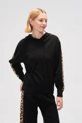 Sweater tipo hoodie de punto color negro, con capucha y cordones ajustables. Presenta bandas laterales en las mangas y en el pantalón con estampado animal print de leopardo.