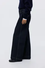 Pantalón de jean estilo wide leg, de tiro alto y corte holgado. Confeccionado en denim rígido de color azul oscuro, presenta costuras a contratono, bolsillos laterales al bies y bolsillos traseros decorativos.