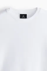 Remera H&M de algodón liviano, color blanco, con cuello redondo y mangas cortas.