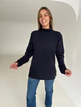 Polera de tejido de punto color negro, con cuello alto, mangas largas y tajos laterales en el ruedo.