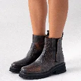 Bota corta estilo chelsea de cuero vacuno negro con acabado desgastado en tono marrón en la puntera y laterales. Presenta elástico lateral, cierre interno y suela de goma tipo track con plataforma.