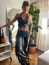 Pantalón negro de cuero sintético con flecos en los laterales.
