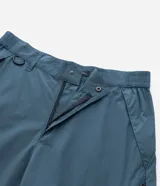 Pantalón de corte holgado en color azul petróleo, confeccionado en microfibra de poliéster. Presenta un diseño utilitario con múltiples bolsillos funcionales, cierres visibles y detalles técnicos en las piernas.