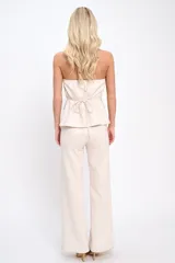 Conjunto de dos piezas compuesto por un top strapless con botones frontales y bolsillos decorativos, y un pantalón de corte recto y tiro alto. Confeccionado en tela con textura suave tipo gamuza.