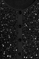Chaqueta de punto negra con lentejuelas brillantes, cuello redondo, manga larga y cierre frontal con botones.