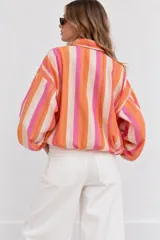 Campera bomber de diseño ligero, con estampado de rayas verticales multicolor en tonos rosado, naranja, fucsia y beige. Presenta cuello alto, cierre frontal completo y mangas largas abullonadas con puños elastizados.