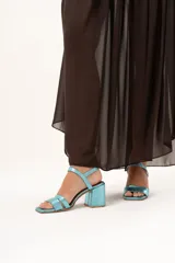 Sandalia de tacón cuadrado medio, color turquesa metalizado, con diseño de tiras anchas en el empeine y cierre con pulsera al tobillo.