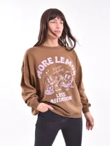 Buzo de cuello redondo y manga larga, color marrón, con estampado gráfico frontal en color lila que incluye texto y personajes animados.