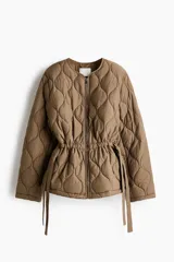 Campera acolchada marrón tipo puffer de nylon guateado, con diseño matelasseado de rombos, cuello redondo y cierre frontal. Cuenta con hombros caídos, mangas largas, bolsillos laterales discretos y cordón de ajuste en la cintura con tiras colgantes.