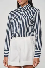 Camisa de manga larga a rayas verticales azul marino y blanco, con cuello clásico, cierre frontal con botones, dos bolsillos con solapa en el pecho y puños abotonados.