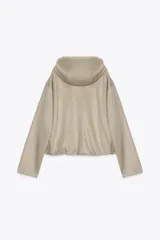 Chaqueta bomber de efecto ante en color marrón, con capucha ajustable mediante cordones, cierre frontal con cremallera, bolsillos laterales y bajo con elástico interior.