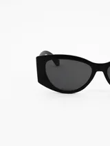 Lentes de sol con armazón de estilo cat-eye moderno en color negro mate y cristales oscuros.