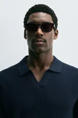 Polo de manga corta, color celeste pálido, con cuello solapa y abertura frontal en V. Tejido de punto con textura acanalada vertical.