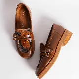 Mocasín de cuero vacuno negro con detalle de pieza de cuero con textura de cocodrilo y hebillas metálicas. Suela de caucho con plataforma.