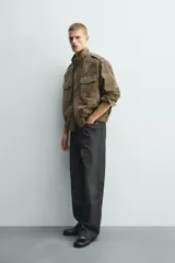 Cazadora de corte relajado confeccionada en piel con acabado de ante. Presenta cuello subido, cierre frontal de cremallera oculta por solapa con botones a presión, bolsillos de plastrón con solapa en el pecho y bolsillos de vivo en la cadera. Incluye trabillas en los hombros, mangas largas con puños abotonados y bajo con elástico.