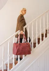 Bolso de mano tipo shopper marca Amadea, confeccionado en cuero con acabado desgastado. Presenta detalles de costuras decorativas verticales, correas con hebillas metálicas doradas y logo grabado al frente.