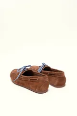 Mocasín tipo boat shoe color marrón, confeccionado en cuero, con cordones de cuero marrón y cordones decorativos azules.