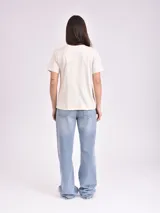 Remera de manga corta color gris topo, con cuello redondo y estampado frontal con temática espacial que incluye texto "YOU ARE MY UNIVERSE" y figuras de estrellas, planetas y platillos voladores.