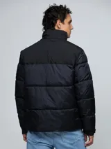 Campera puffer Tommy Hilfiger de color negro, con diseño acolchado, cuello alto y cierre frontal de cremallera. Cuenta con bolsillos laterales con cierre, el logo de la marca bordado en el pecho y un parche con el logo en la manga.