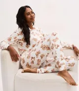 Pijama largo de dos piezas compuesto por una blusa de manga larga con escote redondo y un pantalón con cintura elástica. Presenta un estampado integral de ositos sobre un fondo blanco.