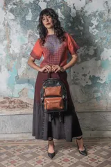 Mochila negra con detalles en marrón, con textura croco en la base y textura graneada en los bolsillos frontales.