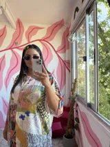 Camisa oversize de seda con estampado patchwork que combina diferentes patrones como cuadros, animal print, rayas y motivos florales. Tiene cuello camisero, botones frontales y mangas cortas.