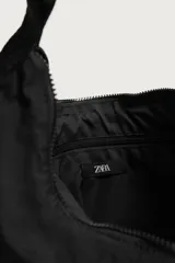 Bolso de hombro negro de tejido técnico, con compartimento principal con cierre de cremallera, bolsillo interior con cremallera y asa de hombro ajustable con detalle de mosquetón.