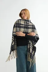 Ruana de tejido suave con diseño de cuadros grandes en tonos azul marino y beige, terminada con flecos en los extremos.