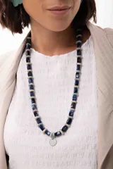 Collar largo compuesto por cuentas rectangulares de acrílico azul y cuentas circulares de piedra natural en tonos grisáceos. Presenta un dije central circular metálico y cierre con cadena de alargue.