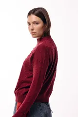 Sweater de tejido de punto con textura de pequeños relieves circulares, cuello redondo y mangas largas. Presenta un calce relajado con puños y ruedo acanalados.