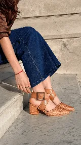 Zapatos de tacón ancho color camel con textura símil serpiente, punta fina y tiras cruzadas con hebilla metálica grande en el lateral.
