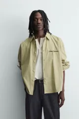 Camisa de corte boxy fit confeccionada en tejido de algodón con estampado de cuadros. Presenta cuello solapa, manga larga con puños abotonados, bolsillo plastrón en el pecho y cierre frontal de botones. Incluye un bordado a contraste en el pecho.