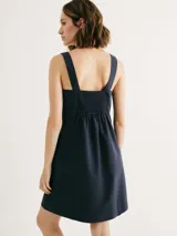 Vestido corto de corte recto con escote cuadrado, tirantes anchos y bolsillos laterales. Diseño minimalista con costura horizontal bajo el busto.