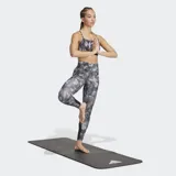 Sujetador deportivo Adidas de sujeción ligera, color gris con estampado abstracto en tonos grises y blancos. Presenta tirantes finos que se cruzan en la espalda y una banda elástica inferior negra.